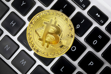 Bitcoin BTC, XBT, cryptocurrency currency and keyboard. Gold metal coin of cryptocurrency, bitcoin. Computer keyboard background. View from above.