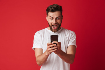 Shocked screaming young man using mobile phone.