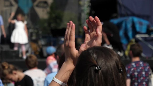 Spectator woman clapping hands by a stage on free religious open air music concert