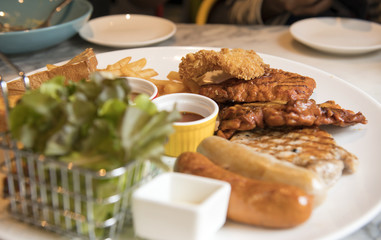 Grilled steak with fried fish, pork and sausage with sauce in the dish and bread are served with a salad streak