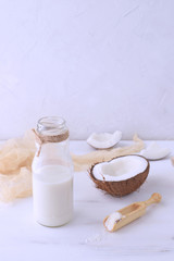Fototapeta na wymiar Organic coconut milk with hafl of fresh coconut on the background