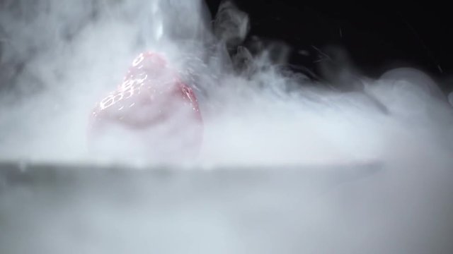 A stream of liquid pours on the berry close up.