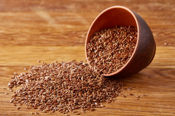 An overturned wooden bowl with linseeds on a rustic background, close-up, shallow depth of field, selective focus