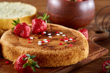 Delicious cake with fresh organic strawberries on cutting board over wooden background, close-up, selctive focus.