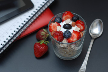 Breakfast for health, fresh strawberries, Blueberies, with oatmeal Black office table. Tablet, laptop and Notebook. Top view. Copy space