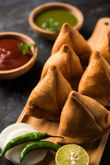 Samosa snack served with tomato ketchup and mint chutney