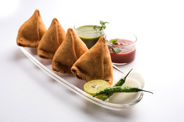 Samosa snack served with tomato ketchup and mint chutney