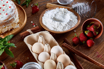 Top view raw ingredients for cooking strawberry pie or cake on wooden table, flat lay. Bakery background.