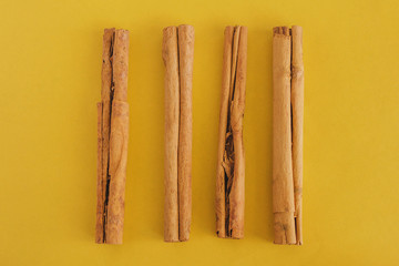 Cinnamon sticks on yellow background