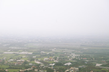 Fototapeta premium Overlooking farmland and streetscape from Qiwei Mountain in Qishan District, Kaohsiung City, Taiwan. The weather is cloudy and visibility is not good in that day.