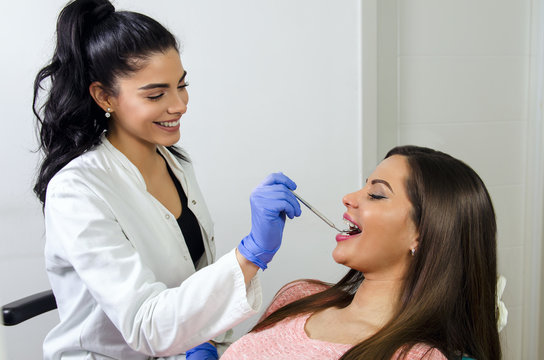 Happy positive female dentist checking braces of her patient 