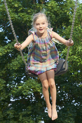  Little child blond girl having fun on a swing outdoor. Summer playground. Girl swinging high. Young child on swing outdoors
