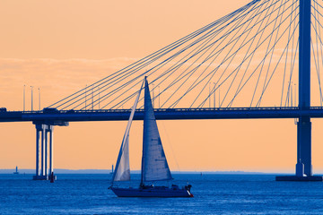 The sailboat sails against the bridge. Sailing. Yacht in the background of the bridge.