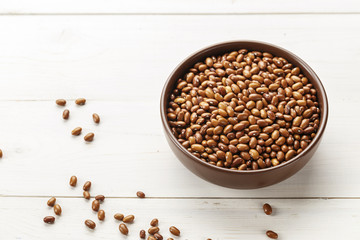 brown beans in a plate on a wooden background
