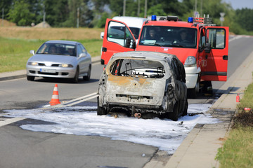 Spalony samochód osobowy na drodze, pożar ugaszony pianą przez straż pożarną. - obrazy, fototapety, plakaty