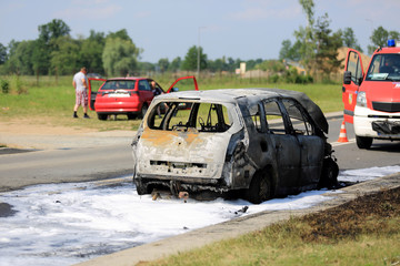Spalony samochód osobowy na ulicy, pożar ugaszony pianą przez straż pożarną. - obrazy, fototapety, plakaty