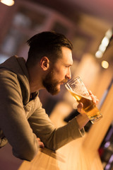 A handsome young hipster man drinking a beer at the bar.