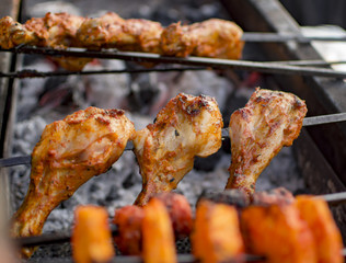 Chicken legs being roasted on fire with steaks