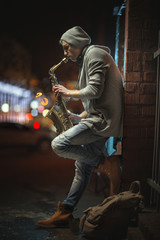 A street musician plays the saxophone in the evening city