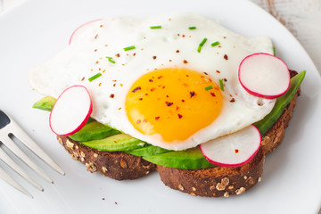 Healthy toast with avocado, fried egg and radish for breakfast