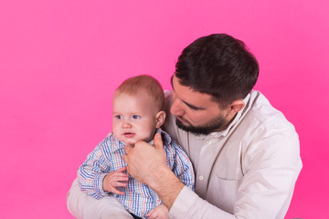 Baby in the daddy hands. Pink background.