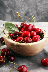 Fototapeta na wymiar Cherry. Red fresh Cherries in bowl and a bunch of cherries on the table