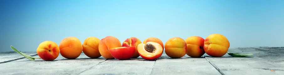 Poster Delicious ripe apricots on wooden table. Fresh cut apricot fruits © beats_