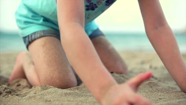 Little girl on the beach, happy little baby playing with sand on the beach. A child, a child, children, emotions.