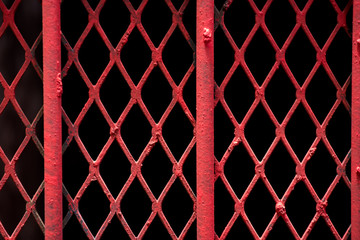 Obraz premium An abstract shot of fine red painted wire lattice on a barred window in Johannesburg inner city