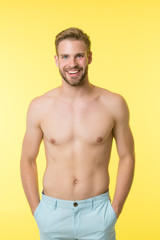 Man on smiling face puts hands in pockets, yellow background. Guy with bristle on face and smooth...
