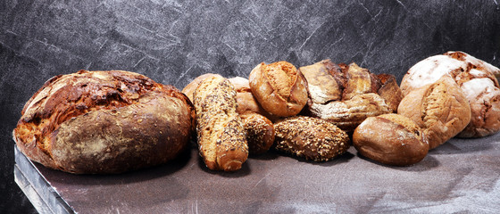 Different kinds of bread and bread rolls on board from above. Kitchen or bakery