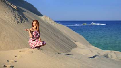 Piękna dziewczyna wypoczywa na piaszczystej wydmie, nad brzegiem morza.