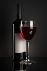 Red wine bottle and full wineglass on black