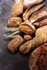 Different kinds of bread and bread rolls on board from above. Kitchen or bakery