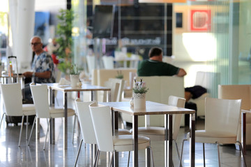 Ludzie przy stolikach w restauracji portu lotniczego. - obrazy, fototapety, plakaty