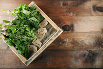 Different fresh herbs in box on brown wooden table
