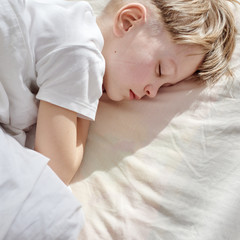 Obraz na płótnie Canvas Top view of young blond boy sleeping at home