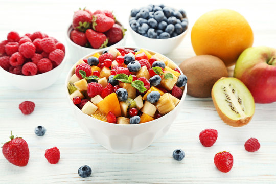Fresh fruit salad in bowl on white wooden table