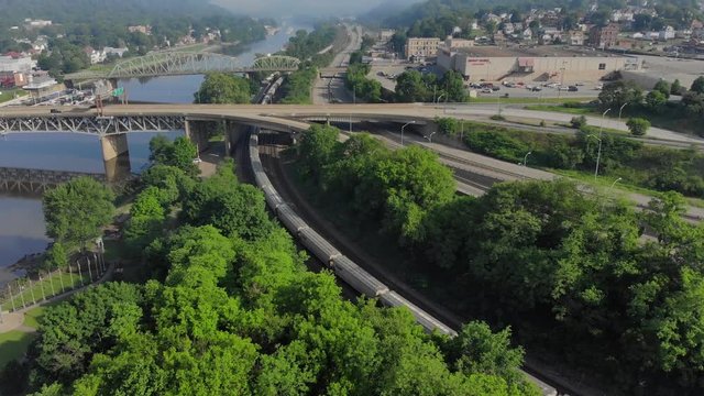 A slow push forward morning aerial establishing shot view of the small town of Rochester, PA as a freight train passes in the foreground.  Pittsburgh suburbs.  	