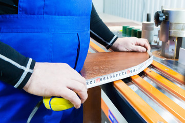 Closeup of Carpenter's hands using one meter in a cottage workshop