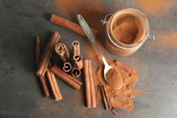 Composition with aromatic cinnamon powder and sticks on grey background