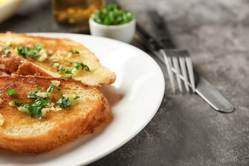 Plate with delicious homemade garlic bread on table