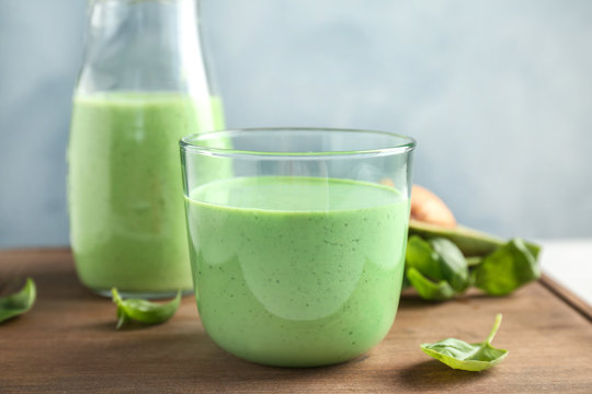 Glassware with healthy detox smoothie and spinach on table