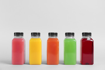 Fototapeta na wymiar Bottles with delicious colorful juices on light background