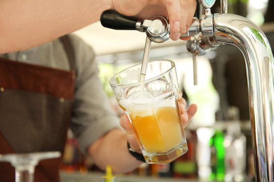 Bartender pouring fresh cold beer from tap, closeup