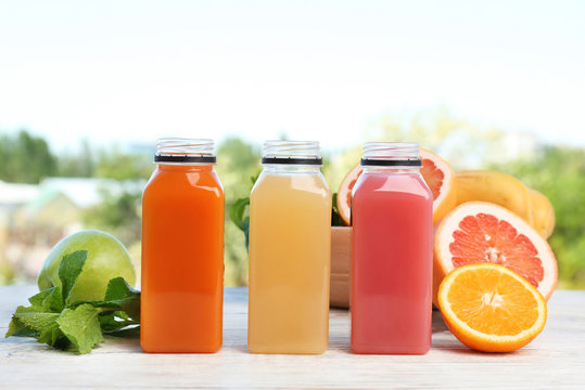 Bottles with tasty juices and ingredients on table