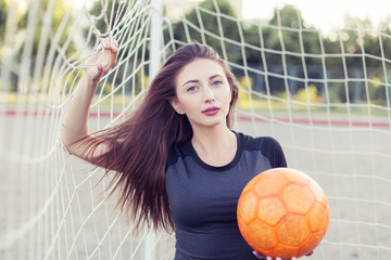Woman with a ball in the corner of the football goal.