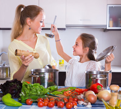 Mother with daughter cooking veggies