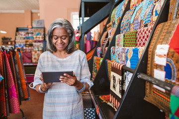 Smiling woman in her fabric shop using a digital tablet