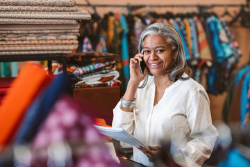 Smiling woman talking on a cellphone in her fabric shop